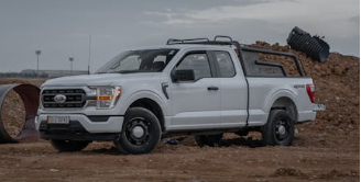A white pickup truck parked at a dusty construction site during an overcast day.